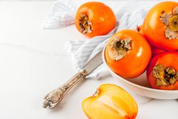 Delicious raw ripe persimmon fruit on white marble background copy space, kaki gesund